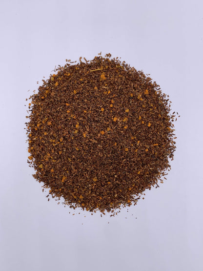 Close-up of a pile of brown flakes scattered on the ground, surrounded by natural outdoor elements, for organic teas.